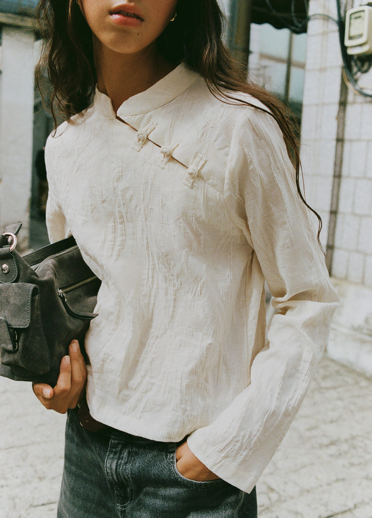Bolso de hombro en gris oscuro con bolsillos frontales y cremallera sobre modelo