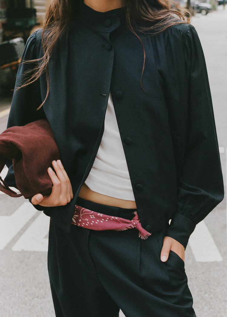 Chaqueta bomber marino con frunces y botones vista sobre modelo con el brazo en el bolsillo