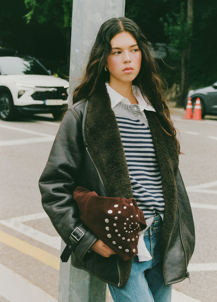 Bolso de hombro marrón con tachas en espiral lucido sobre modelo