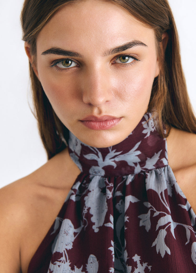 Detalle del escote halter del vestido largo estampado en tono granate sobre modelo