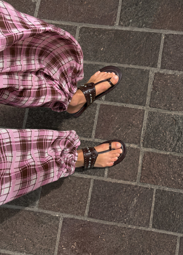Pantalón largo bombacho de cuadros rosa con el bajo recogido sobre sandalias de tiras