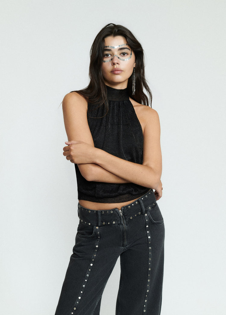 Top halter de brillo en negro sobre modelo con los brazos cruzados