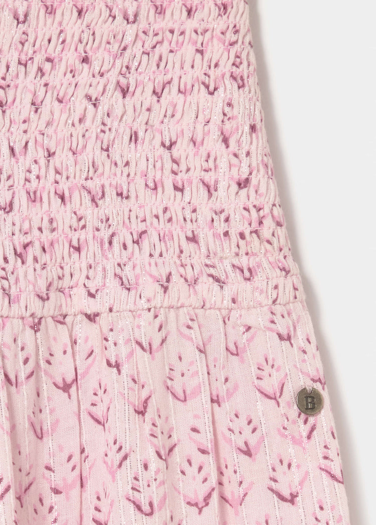 Detalle de la falda larga rosa con estampado floral y botón metálico en la parte inferior