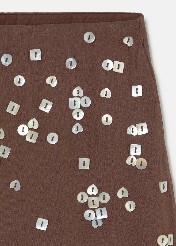 Falda corta de color chocolate con lentejuelas de nácar en formas variadas