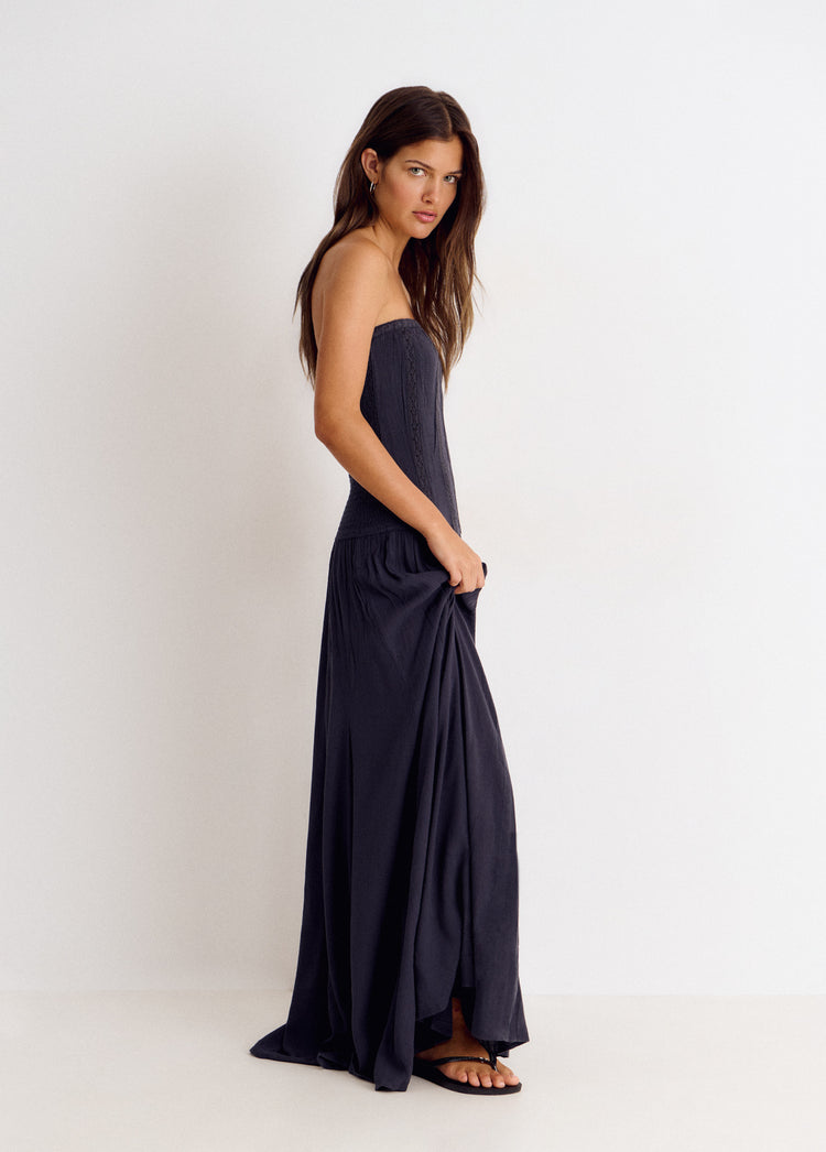 Vestido largo bandeau de encaje antracita visto de perfil con la mano sujetando la falda