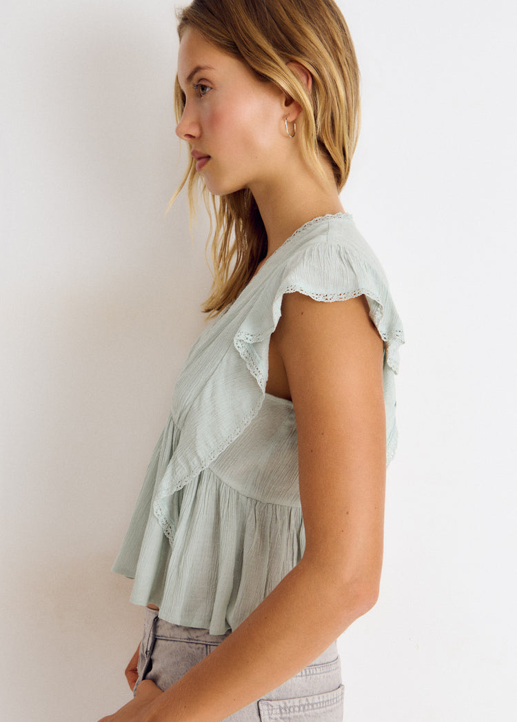 Blusa verde agua con volantes de puntilla vista de perfil