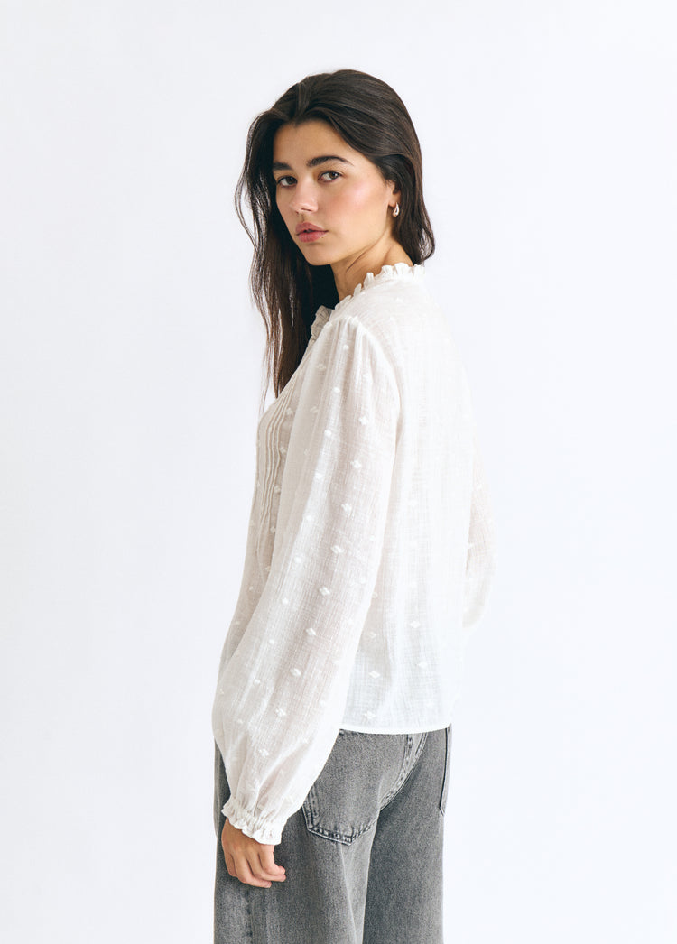 Blusa blanca de manga larga con jaretas y detalles lurex vista lateral sobre modelo