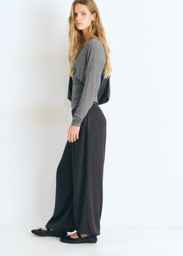 Pantalón bombacho de color antracita con cintura tachada visto de perfil sobre modelo