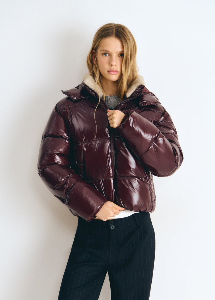 Chaqueta acolchada vinilada de color granate con capucha forrada en pelo y efecto brillante