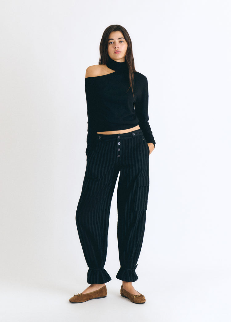 Jersey negro de cuello alto con escote lateral visto de frente sobre modelo