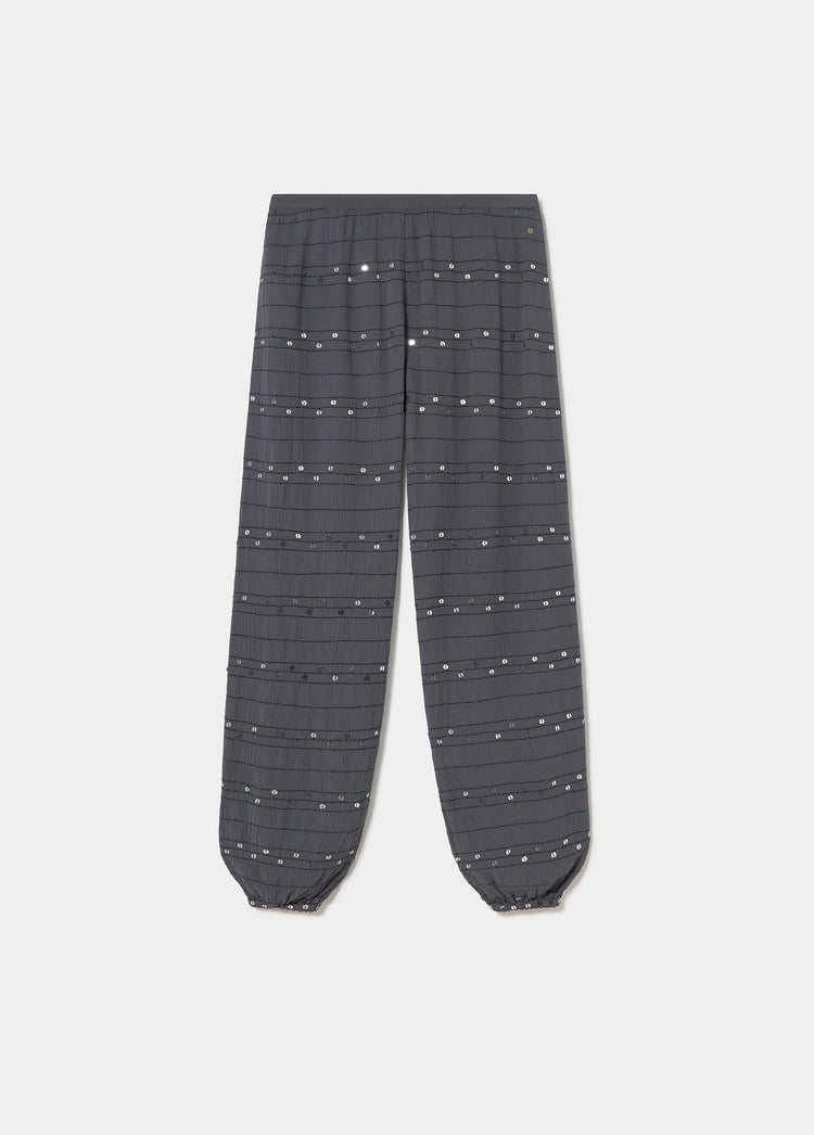 Pantalón bombacho antracita con lentejuelas plateadas distribuidas en líneas horizontales sobre toda la tela