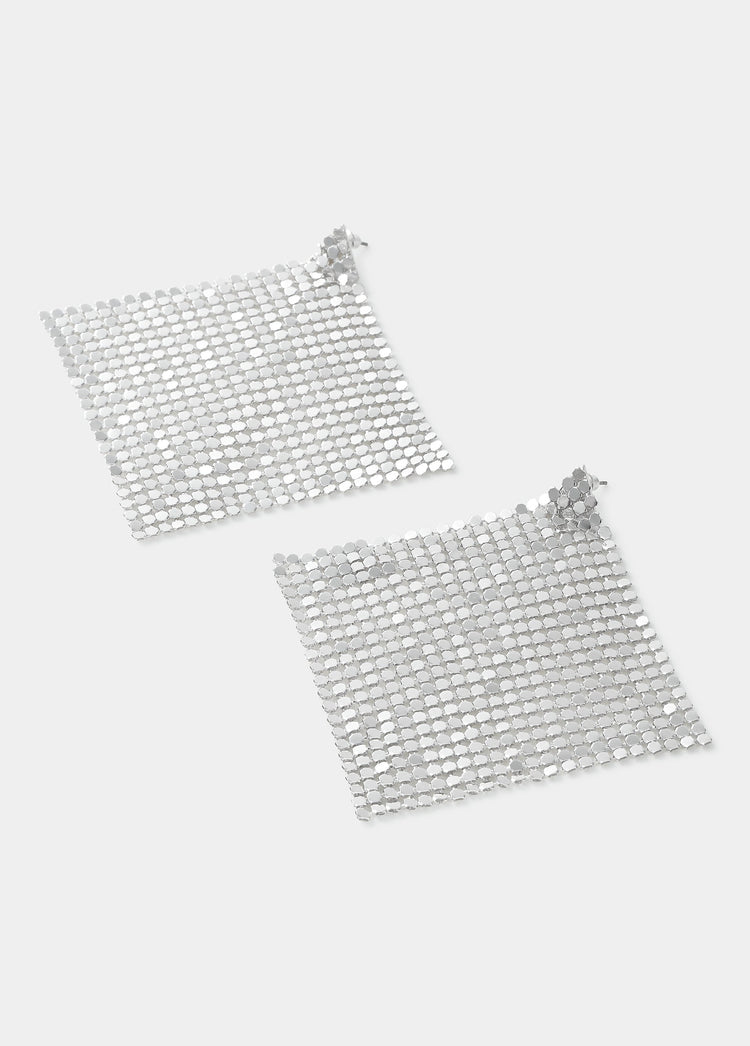 Pendientes de malla metálica en forma de rombo de color plata vistos de frente sobre fondo liso