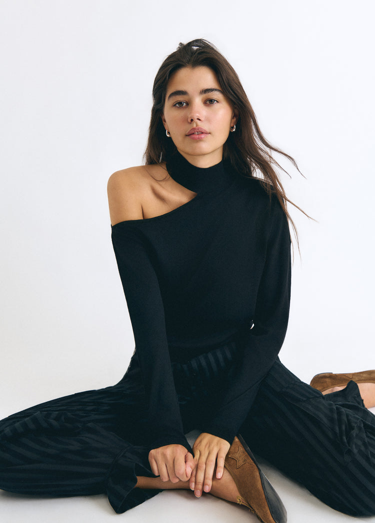 Jersey negro de cuello alto con abertura asimétrica sobre modelo