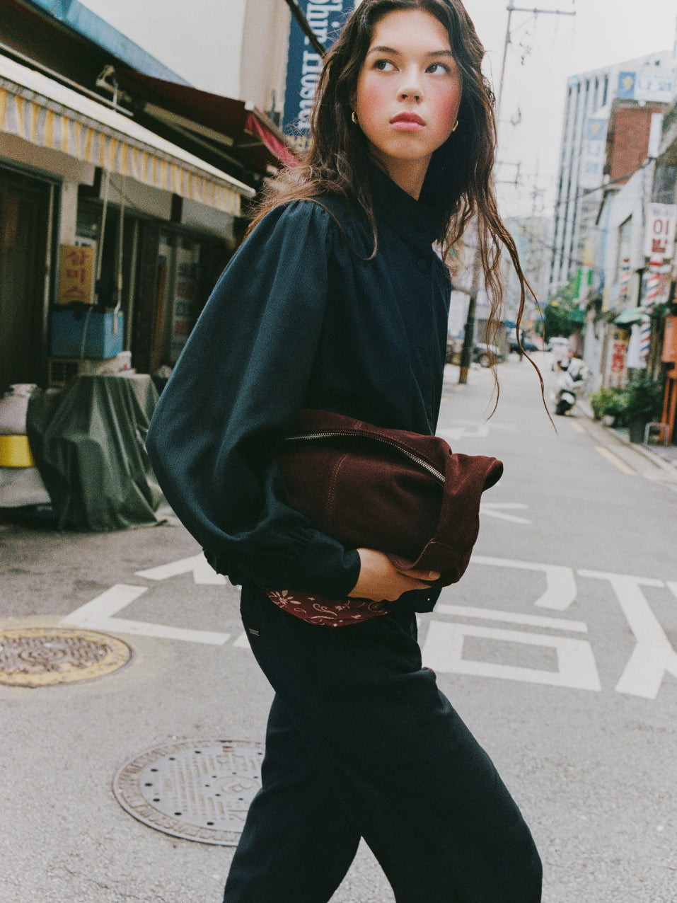 Mujer joven portando un bolso de hombro con estilo de color marrón