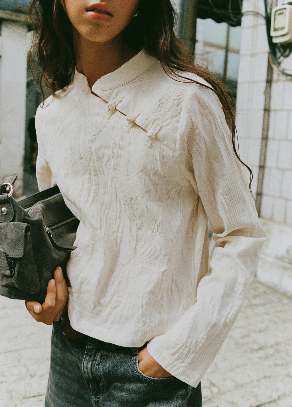 Bolso de hombro en gris oscuro con bolsillos frontales y cremallera sobre modelo