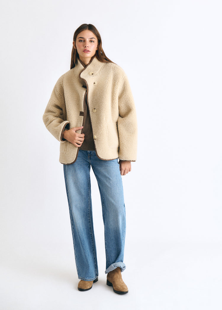 Abrigo reversible doble faz de color avellana luciendo su caída recta sobre modelo