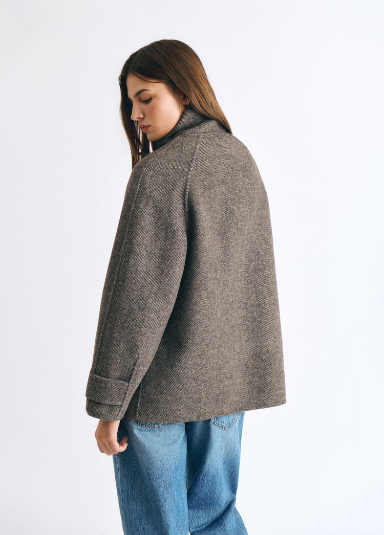 Abrigo de lana color topo con cuello subido visto desde atrás sobre modelo