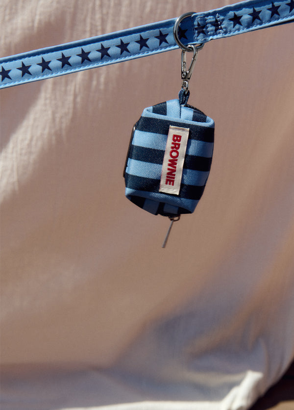 Dispensador de bolsas para mascota en azul con etiqueta de la marca colgando de la correa