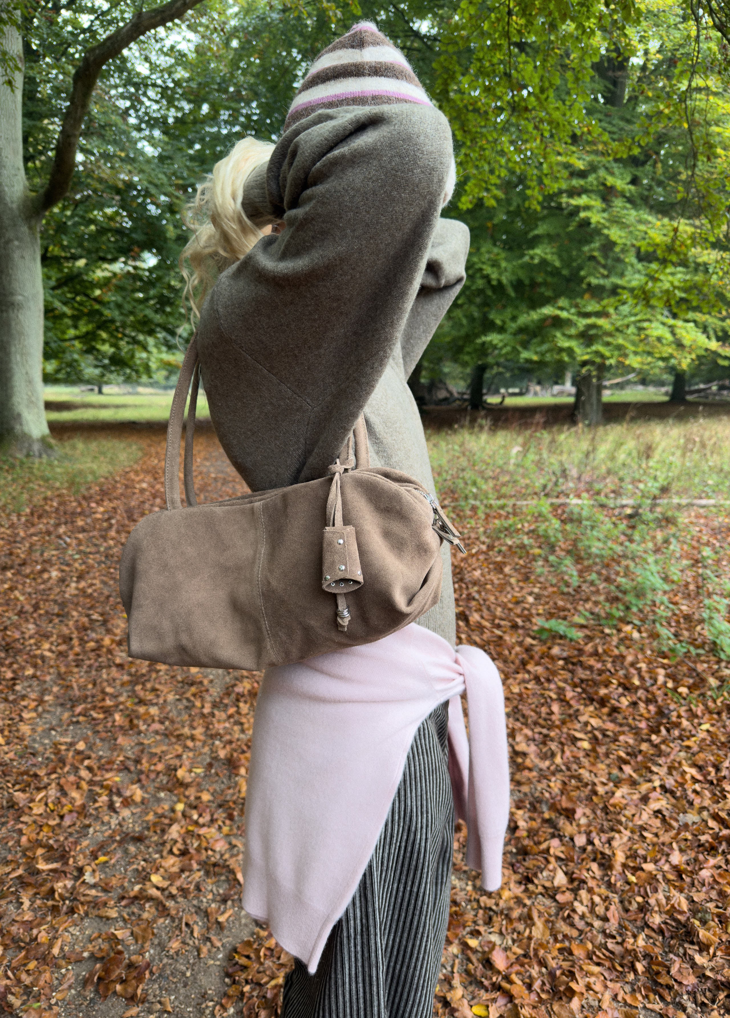 Bolso baguette de color taupe luciendo sus charms sobre modelo
