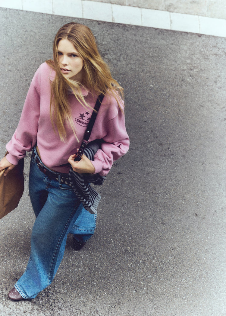 Sudadera de cremallera en rosa luciendo el estampado de estrellas en el pecho sobre modelo