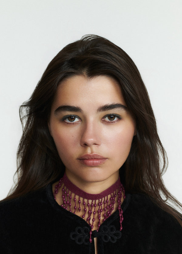 Choker de tejido fino con colgantes de cuentas en tono granate lucido sobre modelo