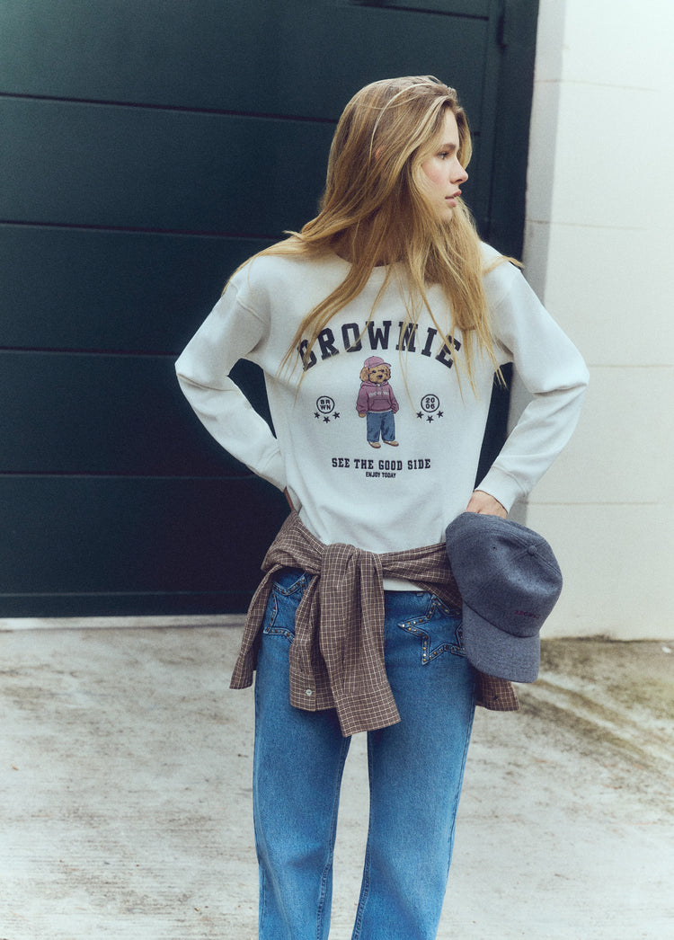 Sudadera de color crudo con estampado de un perro y la palabra brownie lucida sobre modelo