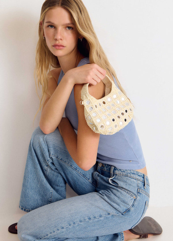 Bolso pequeño de crochet en tono crudo con apliques de espejos redondos luciendo su forma semicircular