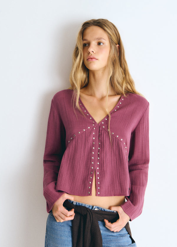 Blusa de manga larga en tono rosado con escote en V y detalles de tachas