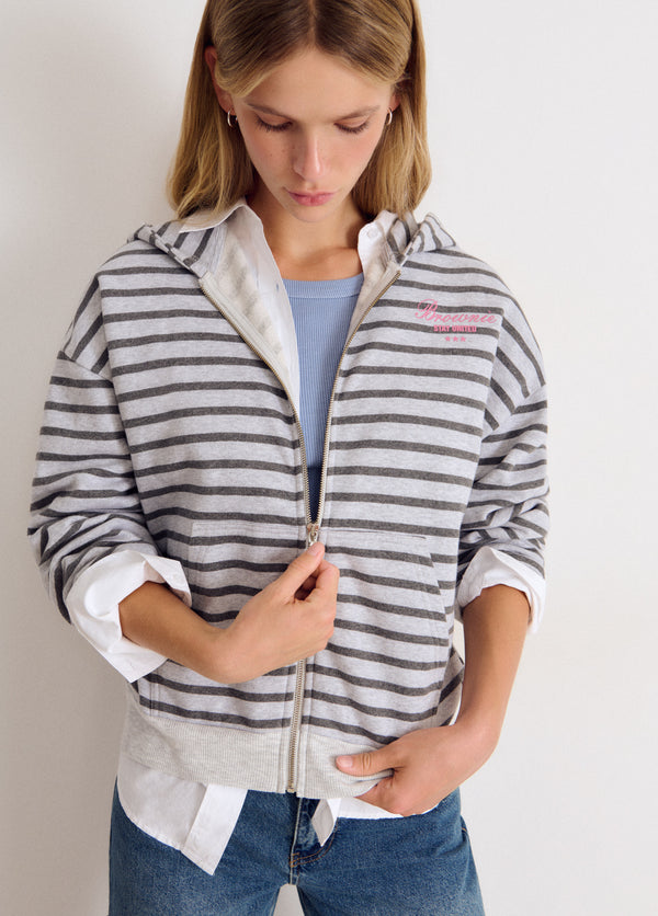 Sudadera de cremallera en gris con rayas y bordado rosa, vista frontal con capucha y mangas recogidas