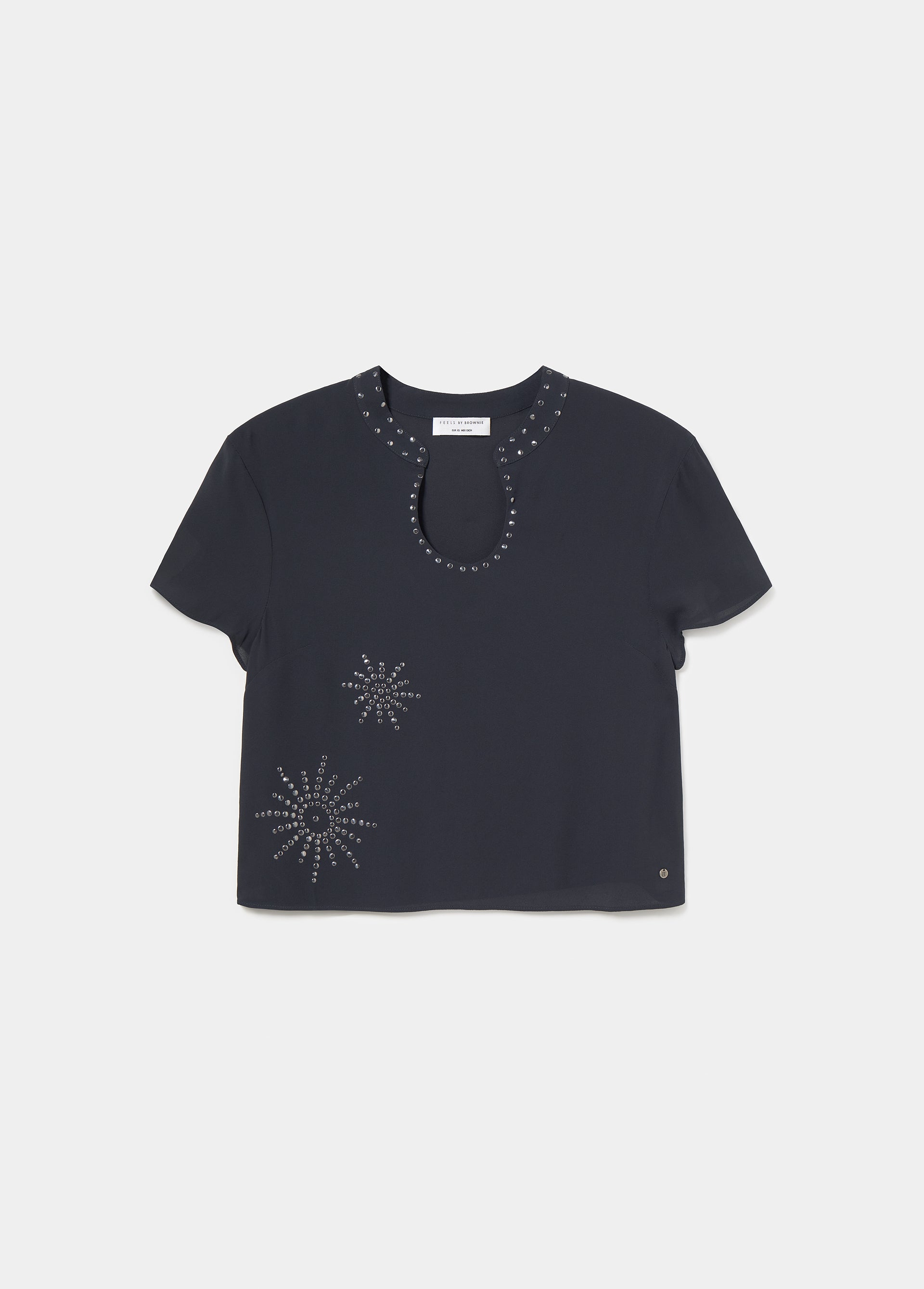 Blusa de manga corta en negro con cuello y escote decorados con tachas plateadas sobre modelo