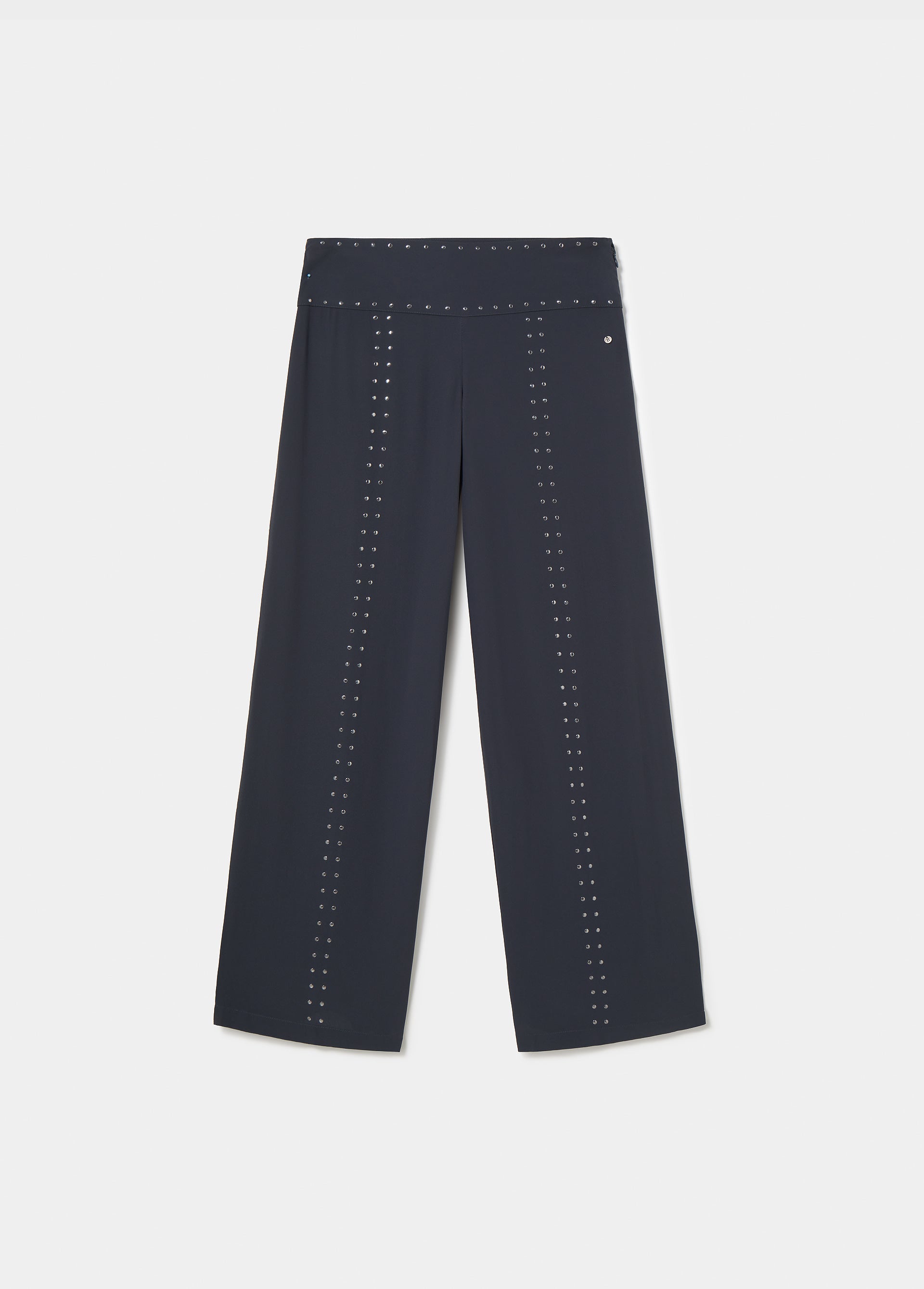 Pantalón largo negro de corte amplio con detalles de tachas sobre modelo