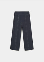 Pantalón largo negro de corte amplio con detalles de tachas sobre modelo