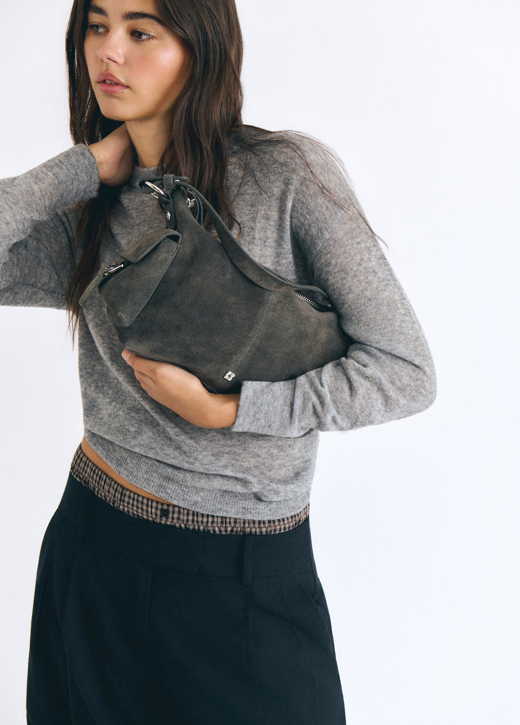 Bolso de hombro en gris oscuro con bolsillos, luciendo su frente sobre modelo