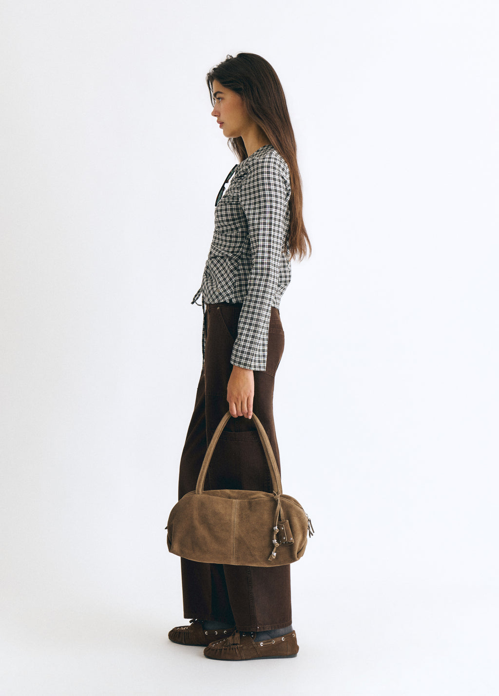 Bolso baguette de color taupe visto de perfil sobre modelo