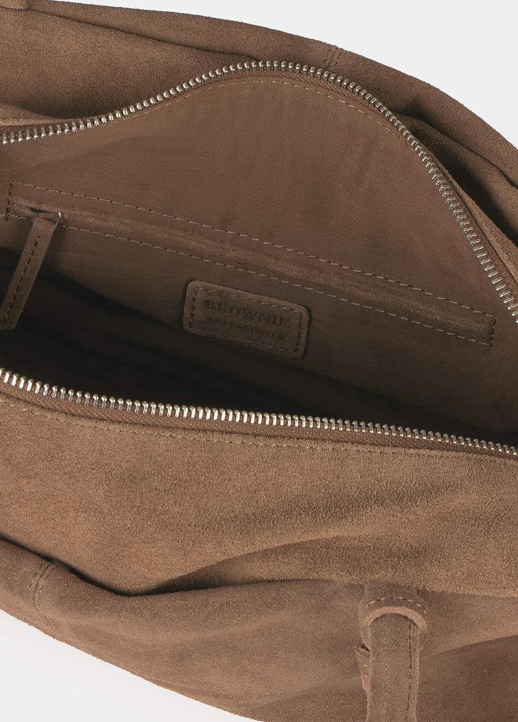 Interior del bolso baguette en ante taupe con cremallera metálica y etiqueta de la marca visible