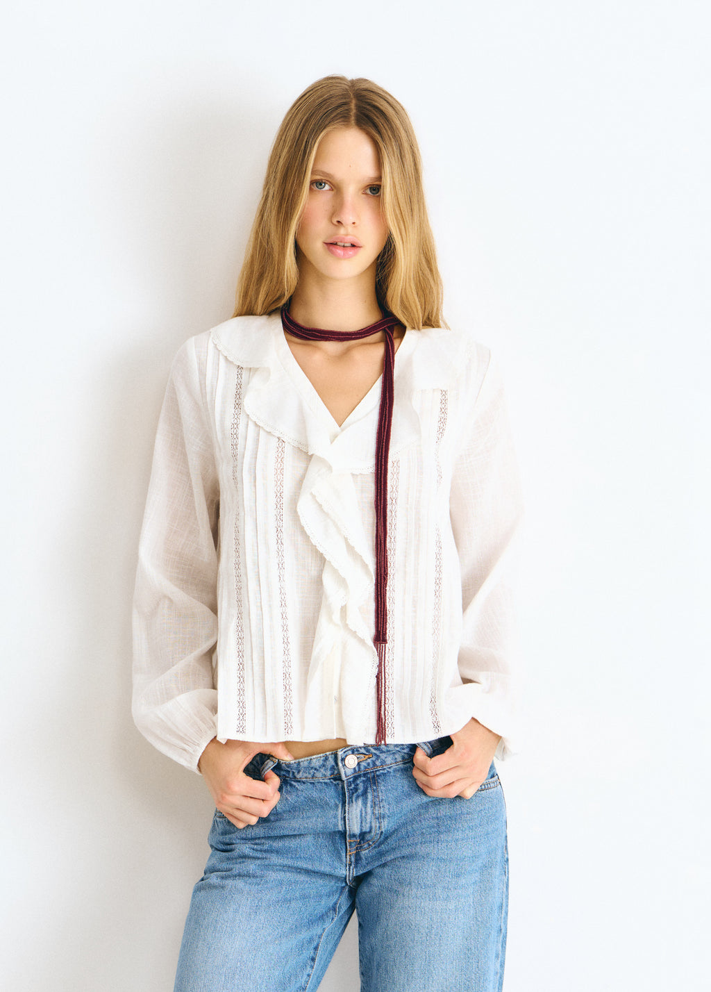 Blusa blanca de manga larga con volante central y detalles de lurex vista de frente