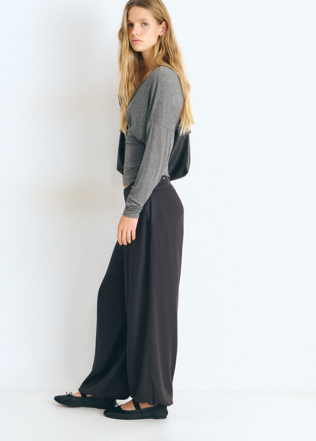 Pantalón bombacho de color antracita con cintura tachada visto de perfil sobre modelo
