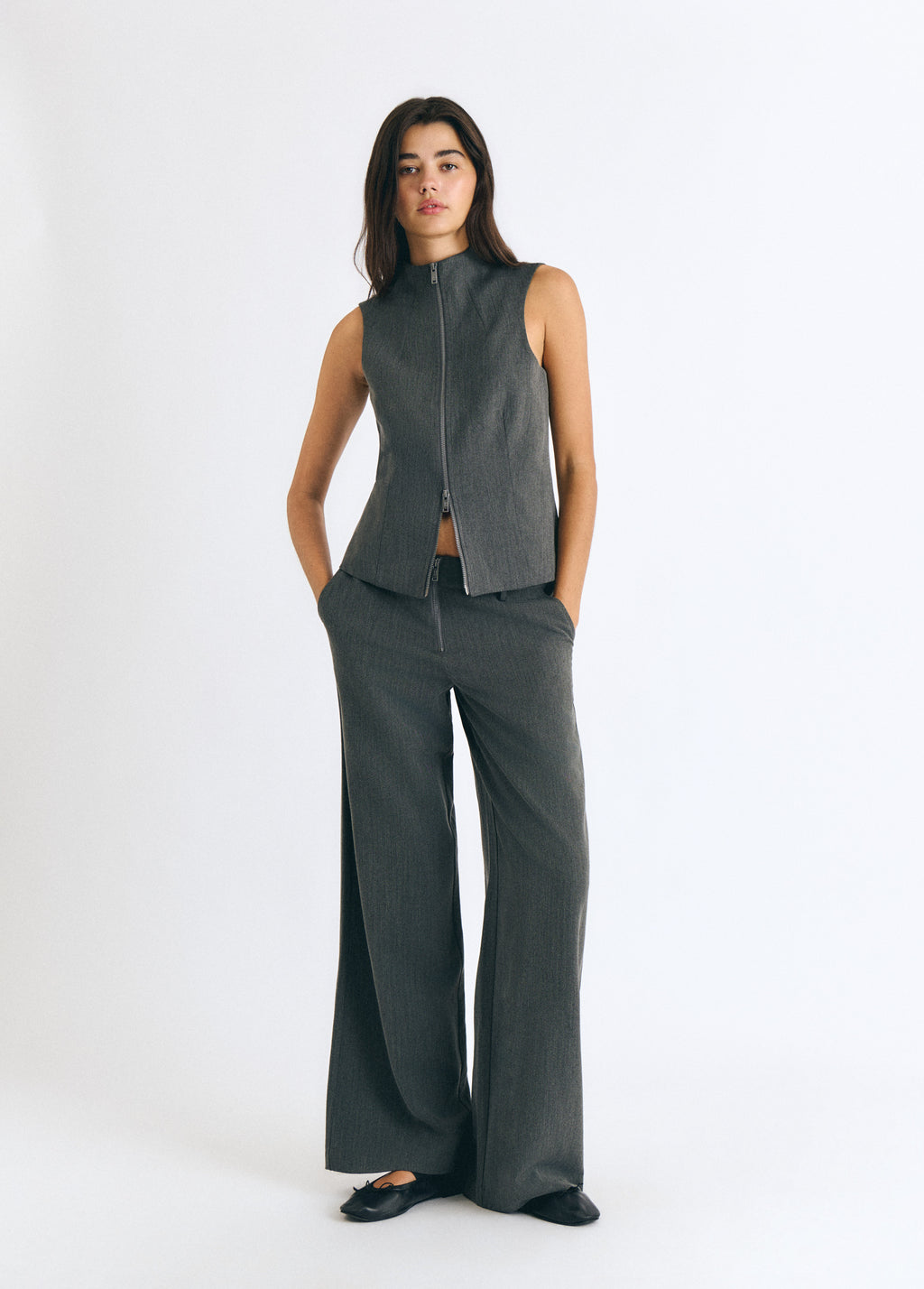 Pantalón gris de corte amplio con detalle de cremallera sobre modelo