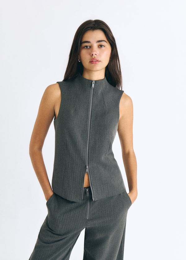 Top gris sin mangas con cuello alto y cremallera frontal vista sobre modelo
