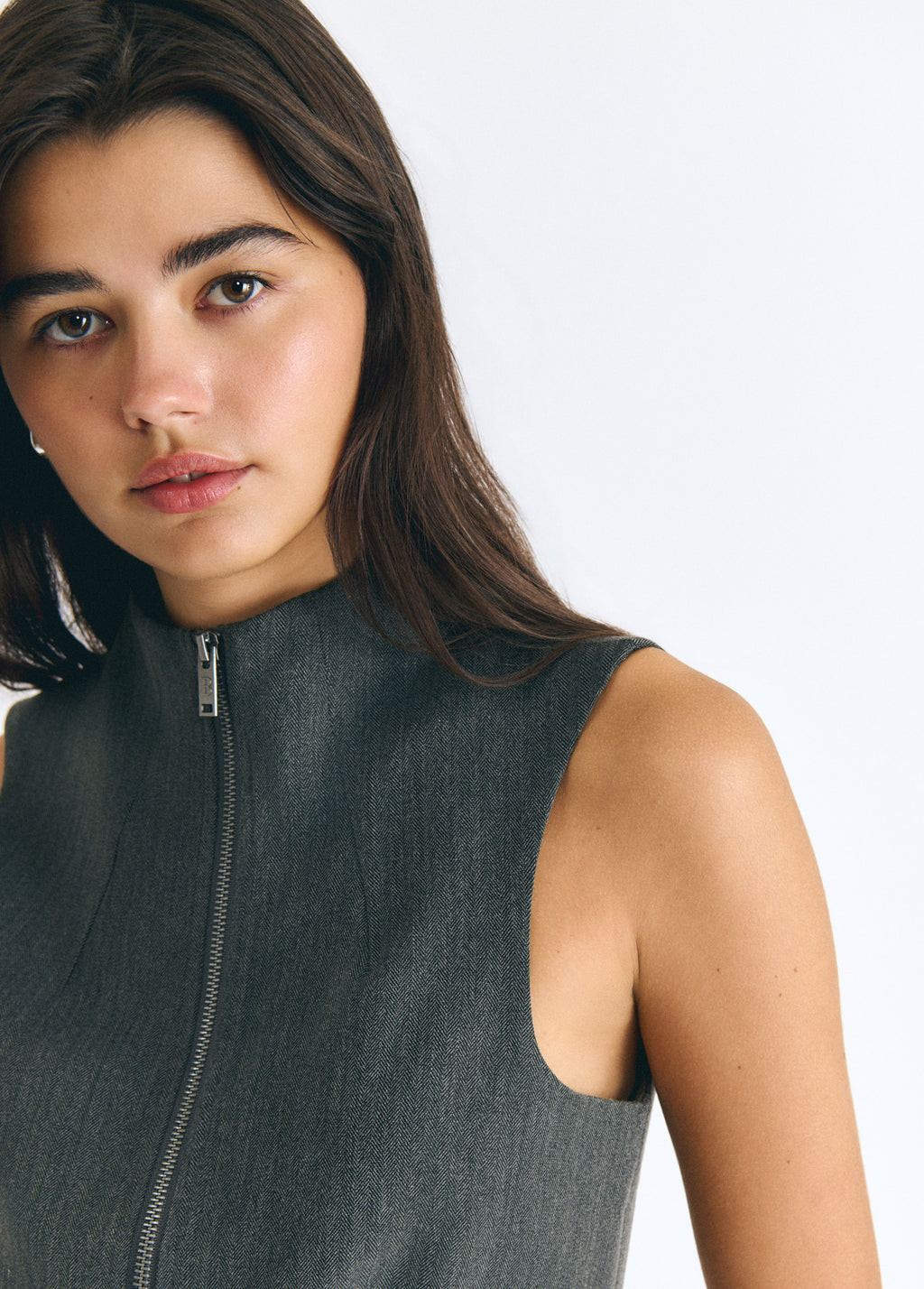 Top gris sin mangas con cremallera frontal y cuello alto mostrando su textura sobre modelo