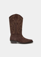 Bota cowboy de serraje en color chocolate luciendo su perfil lateral con el talón apoyado en el suelo