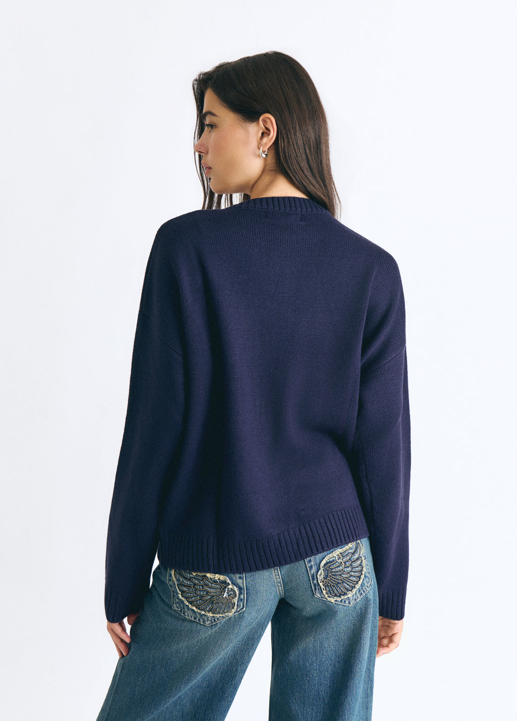 Jersey marino de punto visto por la espalda sobre modelo con vaqueros decorados