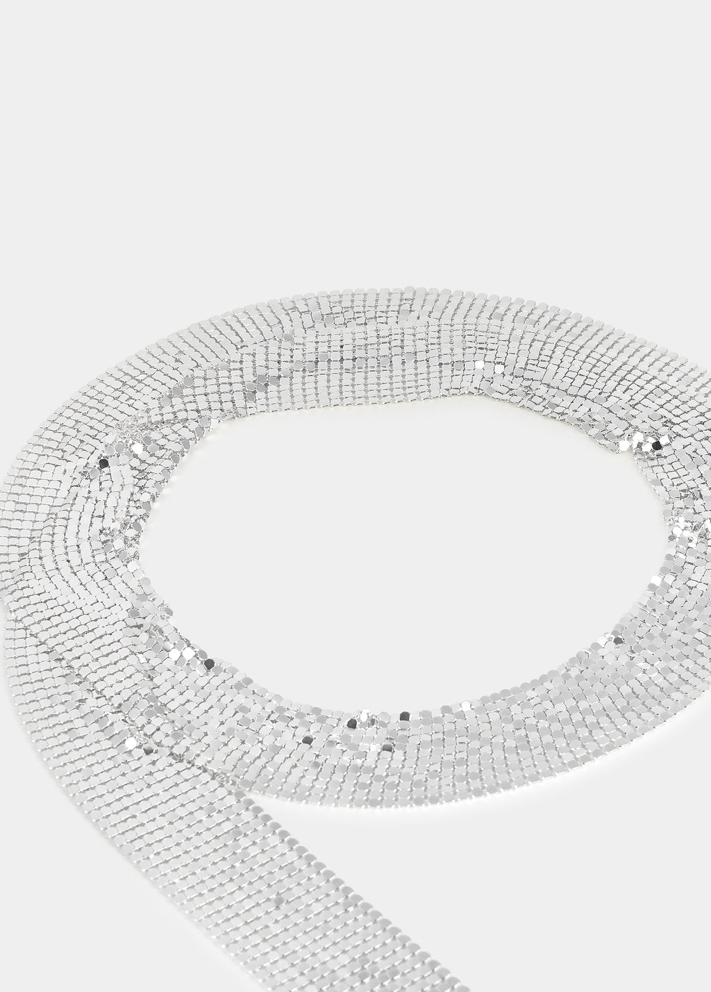 Collar de malla metálica de color plata fotografiado en espiral sobre fondo liso