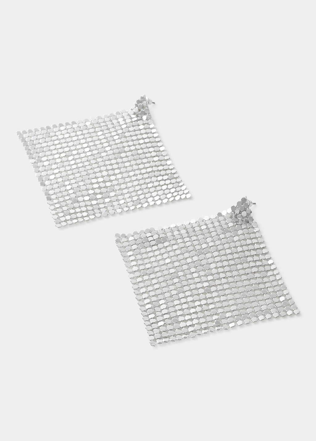 Pendientes de malla metálica en forma de rombo de color plata vistos de frente sobre fondo liso