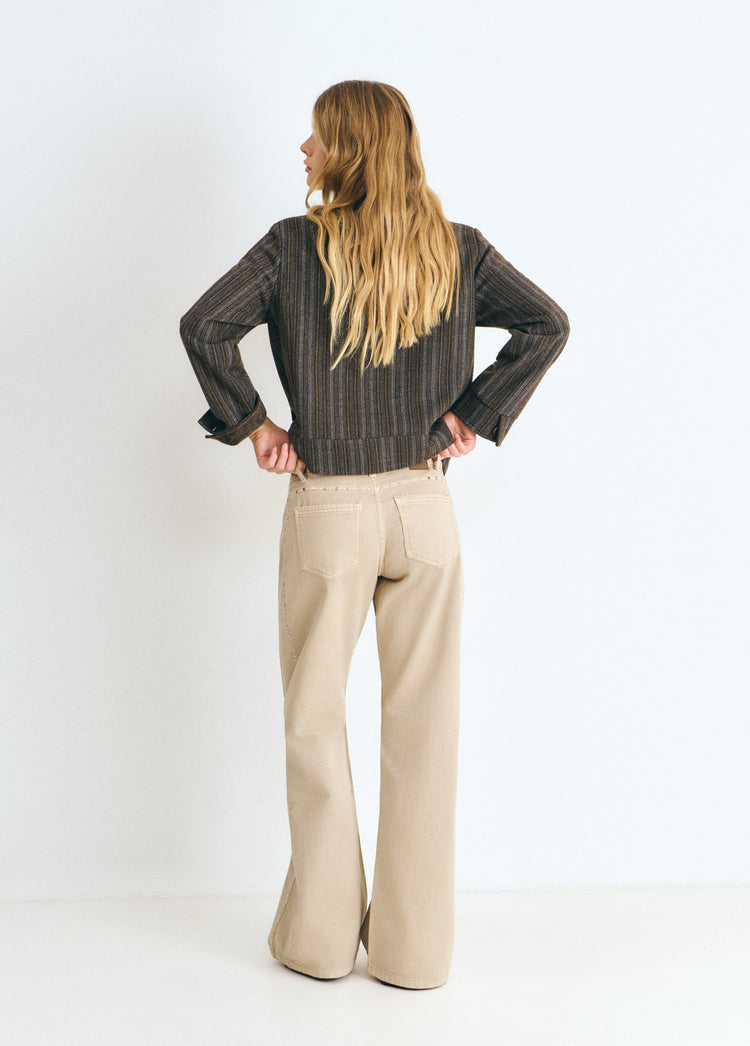 Pantalón recto de color arena con tachas decorativas visto por detrás sobre modelo