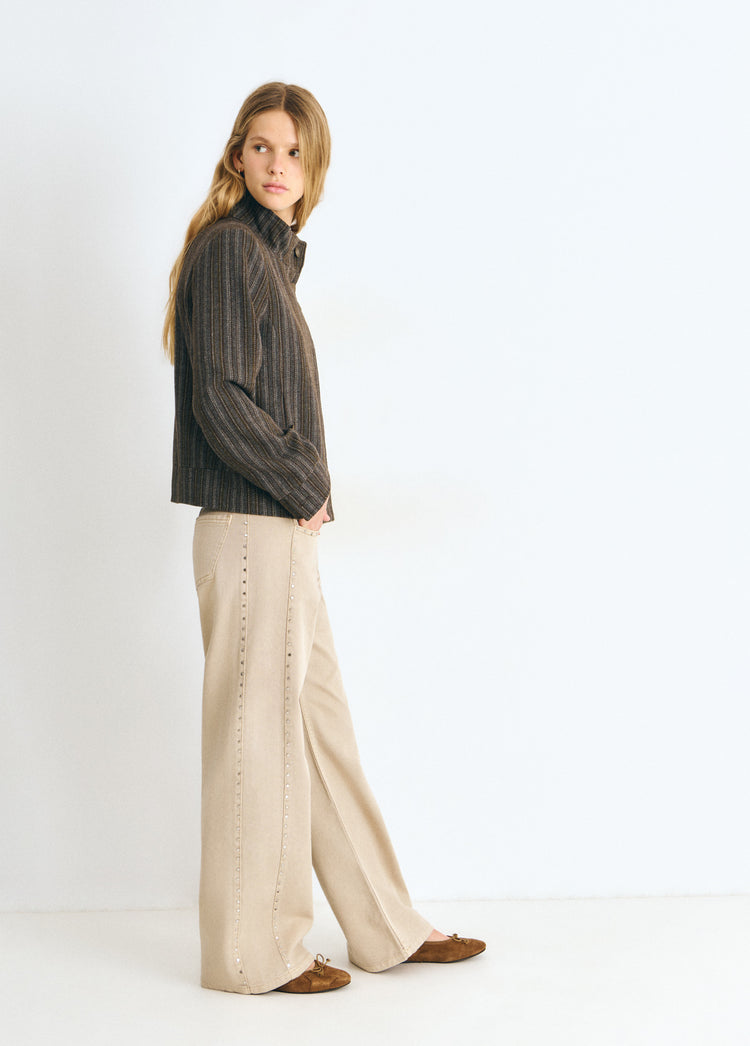 Pantalón recto de color arena con tachas decorativas sobre modelo