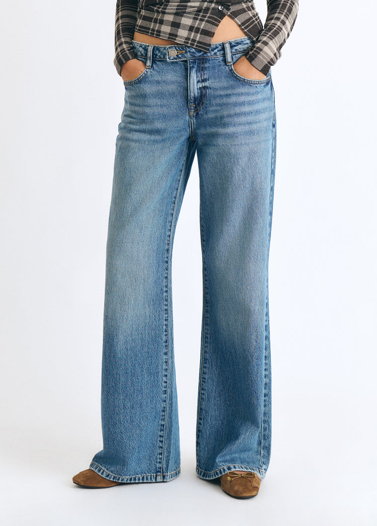Jeans vaqueros de tiro medio y corte ancho en azul oscuro vistos de frente sobre modelo
