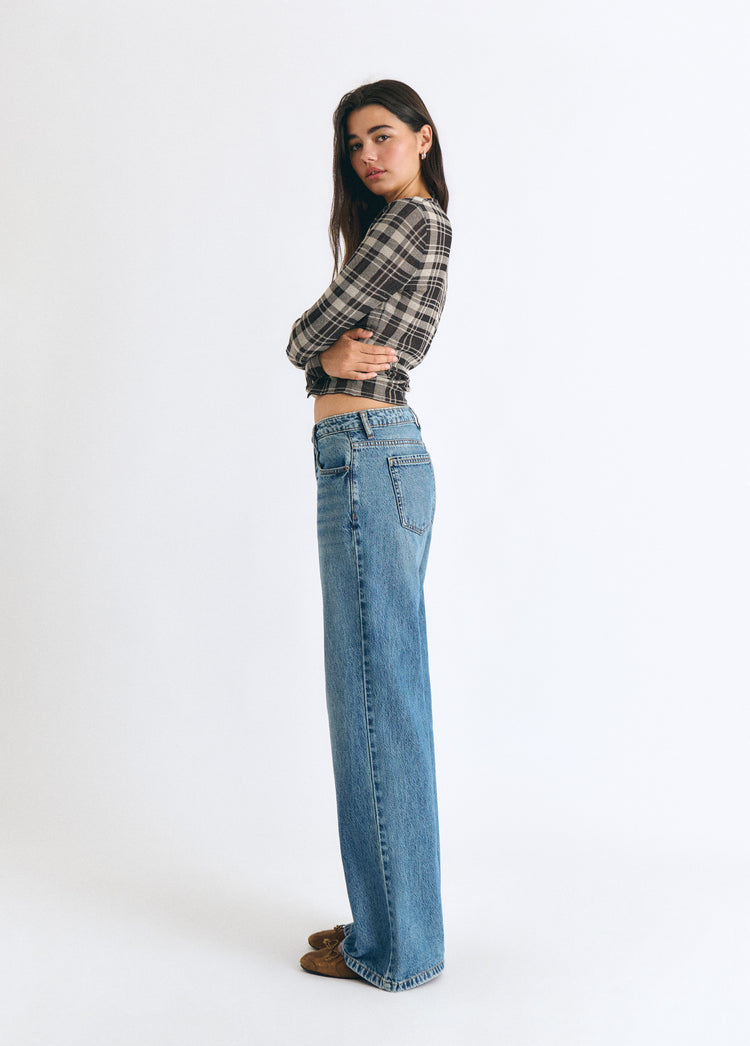 Jeans vaqueros de tiro medio y corte ancho en azul oscuro vistos de perfil sobre modelo