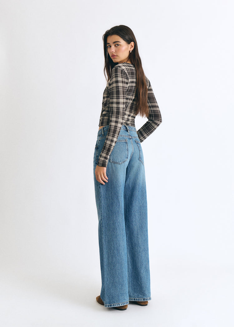 Jeans vaqueros de tiro medio y corte ancho en azul oscuro vistos de perfil sobre modelo