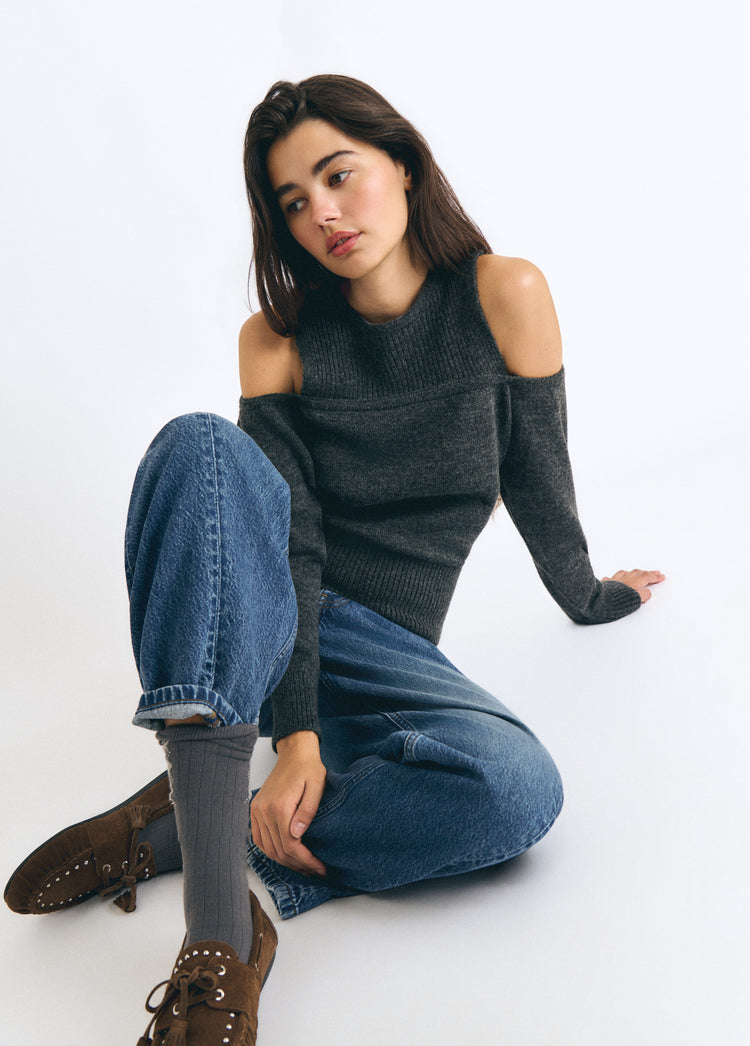 Jersey de cuello alto y hombros descubiertos en gris oscuro sobre modelo